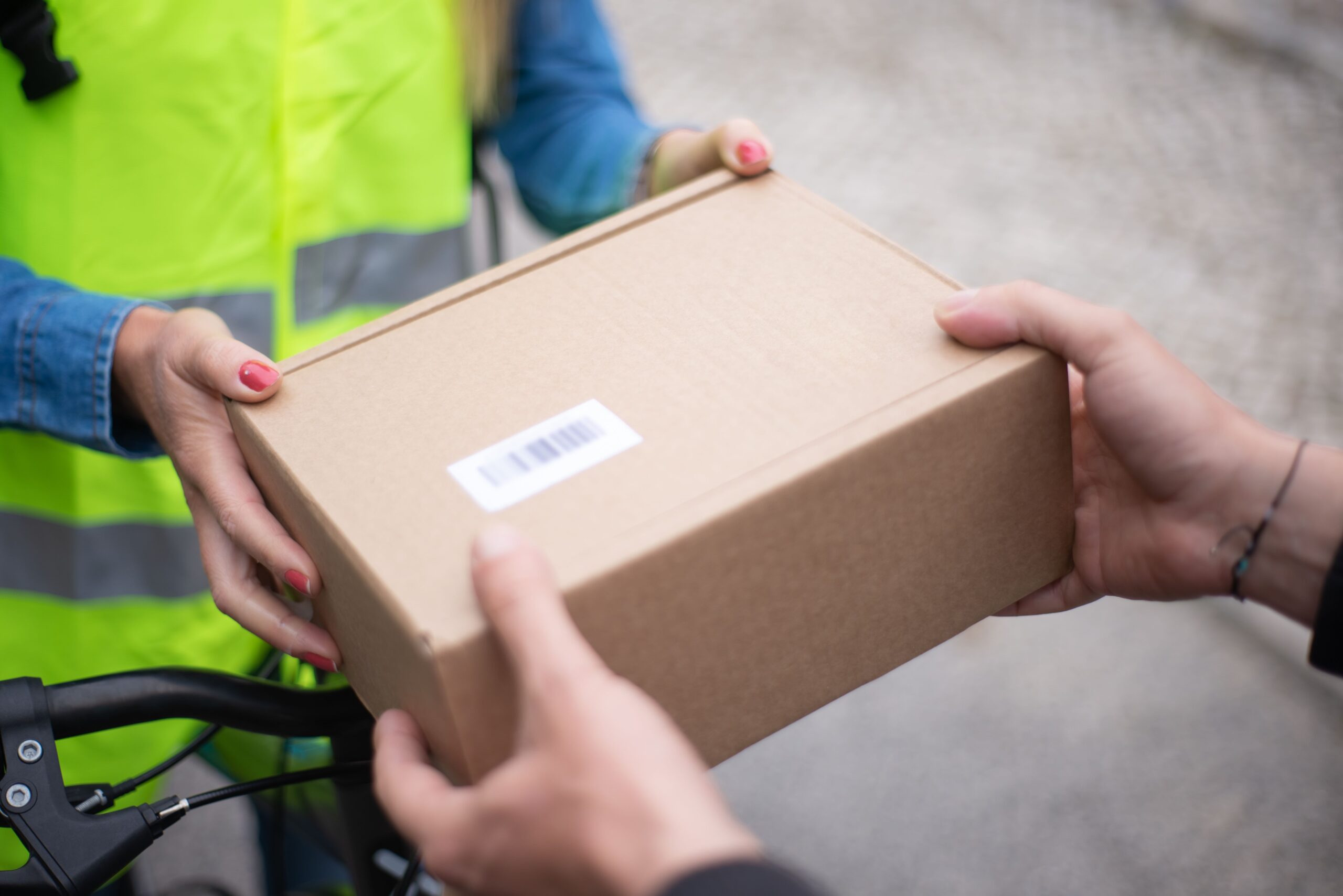 Close-up of hands exchanging a cardboard box outdoors, symbolizing delivery service in Portugal.